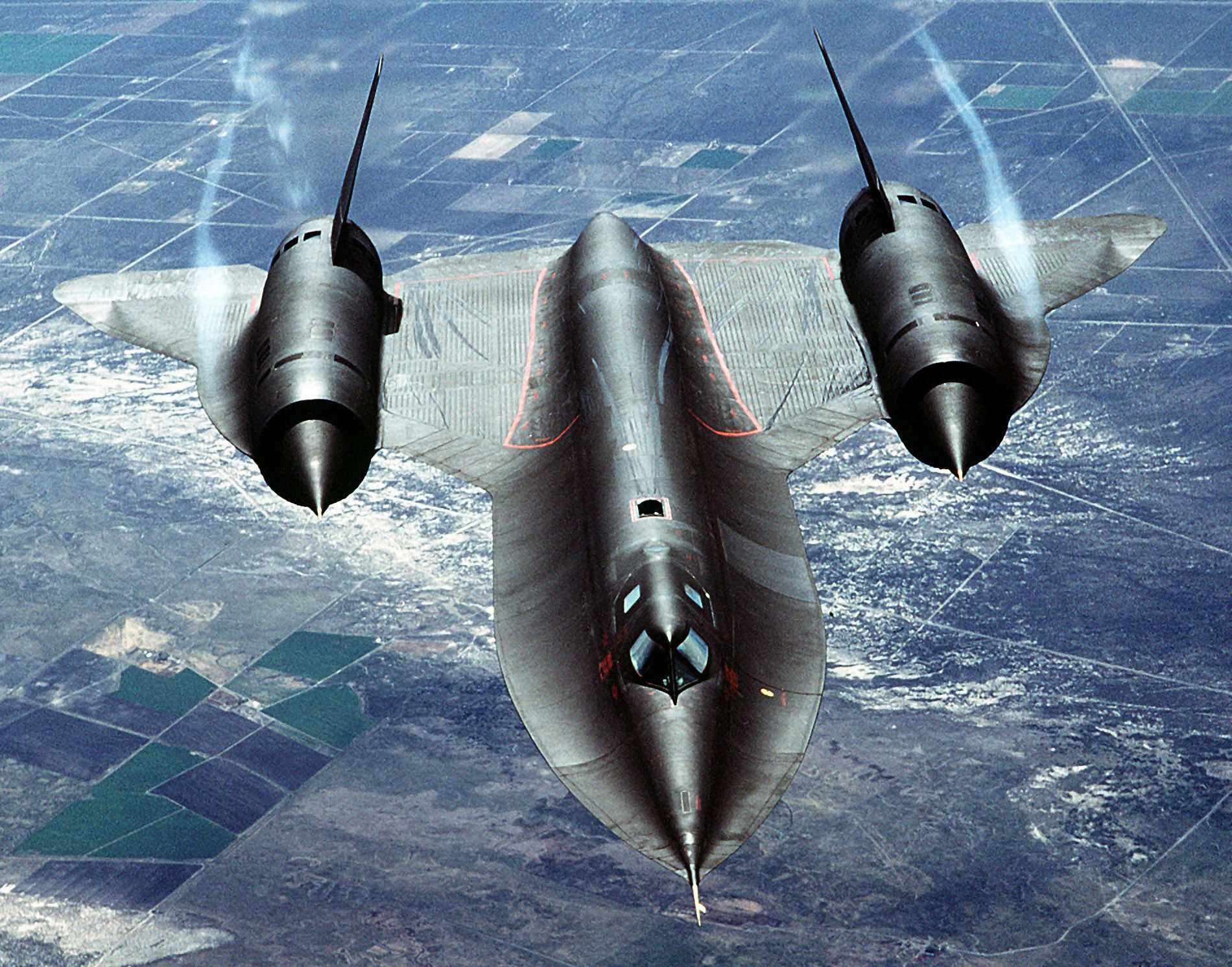 A black SR-71 Blackbird seen head-on from above, vapor trailing from its two engines